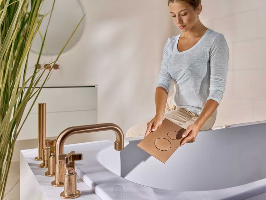 Woman in the bathroom with Sigma40 actuator plate in brushed copper, colour-matched to the fittings Woman in the bathroom with Sigma40 actuator plate in brushed copper, colour-matched to the fittings