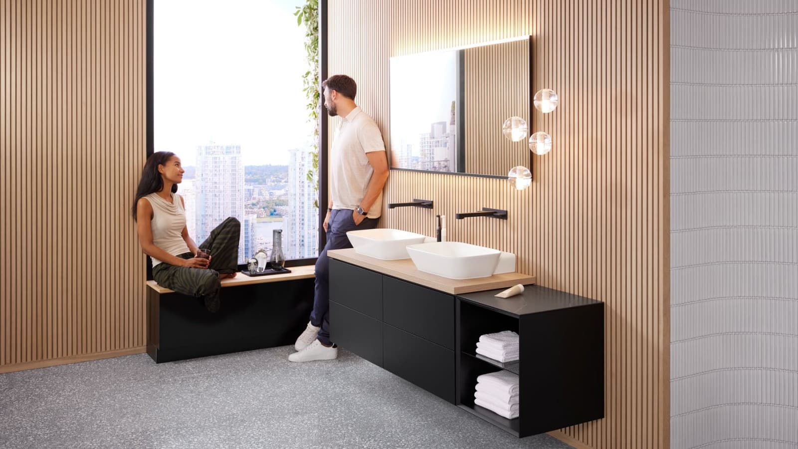 A woman and a man in a large bathroom with Geberit ONE double washbasin, Option mirror and wooden elements A woman and a man in a large bathroom with Geberit ONE double washbasin, Option mirror and wooden elements